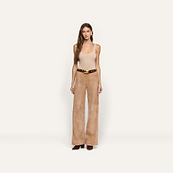 A person wearing a beige tank top and wide-leg suede pants accessorized with a Milou Belt in leopard print Italian calf hair with a large gold buckle.