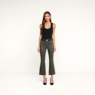 A woman stands facing forward against a plain white background, wearing a sleeveless black top, olive green flared pants, black heels, and accessorized with the Milou Belt.