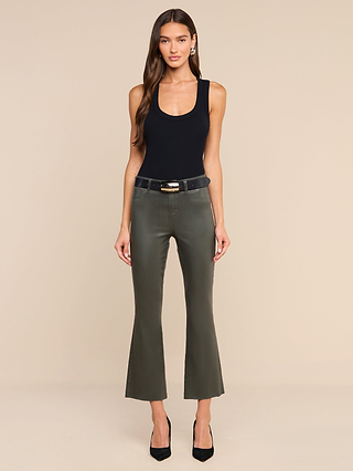 A woman stands against a beige background, dressed in a black sleeveless top, olive-green cropped pants, and black heels. She accessorizes with the Milou Belt—a black lizard-embossed leather belt with a sterling silver-plated buckle, handcrafted in LA. Her long brown hair is worn down, and she opts for minimal accessories and a neutral expression.