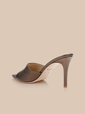 The Lolita Leather Open-Toe Mule features a single pointed toe, high stiletto heel, and bronze lizard-embossed leather, displayed against a beige background.