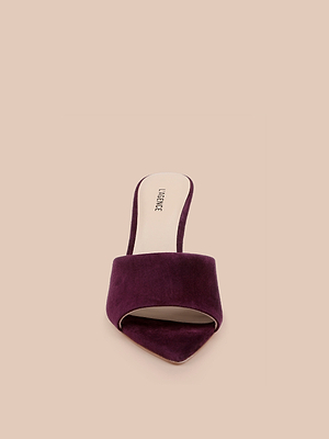 The Lolita Suede Open-Toe Mule, shown in burgundy suede with a pointed toe and open back, is displayed against a plain beige background.