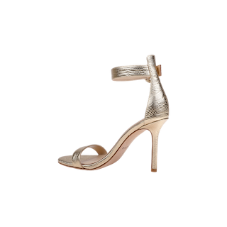 The Gisele Leather Sandal, a single gold high-heeled sandal with a textured metallic finish, ankle strap with back zipper, and open toe—ideal for wedding guests—is displayed against a plain white background.