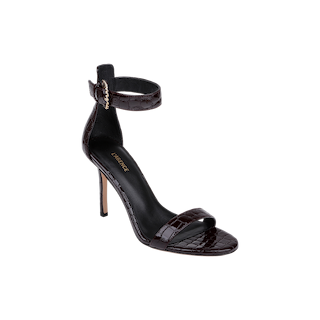 The Gisele Leather Sandal is a black high-heeled sandal crafted from crocodile-embossed leather, showcasing a thin ankle strap with a gold buckle, an open toe, and a single front strap—an embodiment of sophisticated elegance.