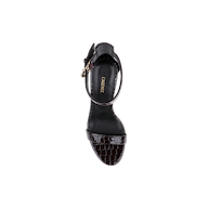 A black Gisele Leather Sandal, crafted with crocodile-embossed leather and an ankle strap adorned with a gold buckle, is displayed from above against a white background. The insole features the LARGRICE logo in gold lettering.