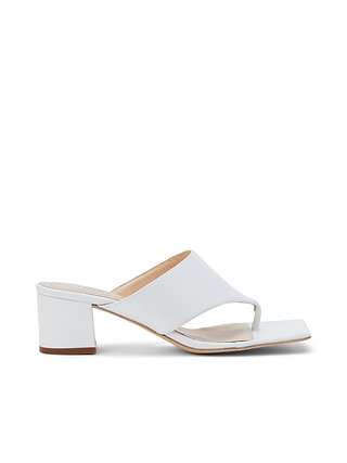 The Estelle Sandal is crafted from white leather and features an open toe, wide strap, and a low block heel. With a chunky, minimalist design that includes a toe loop and a slightly squared sole, the Estelle Sandal is showcased against a plain white background.