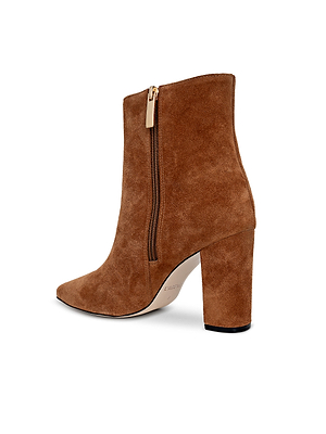 The Theodora Block-Heel Bootie by L'AGENCE features brown buckskin suede, a pointed toe, side zipper, and a stylish high block heel, shown against a white background.