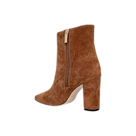 The Theodora Block-Heel Bootie is a tan buckskin suede high-heeled ankle boot featuring a pointed toe, sturdy block heel, and convenient side zipper, shown against a plain white background.
