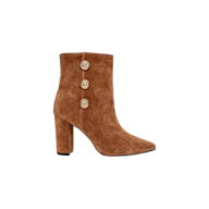 The Theodora Block-Heel Bootie is a brown buckskin suede ankle boot featuring a high block heel, a pointed toe, and three decorative gold buttons along the side. The background is plain white.