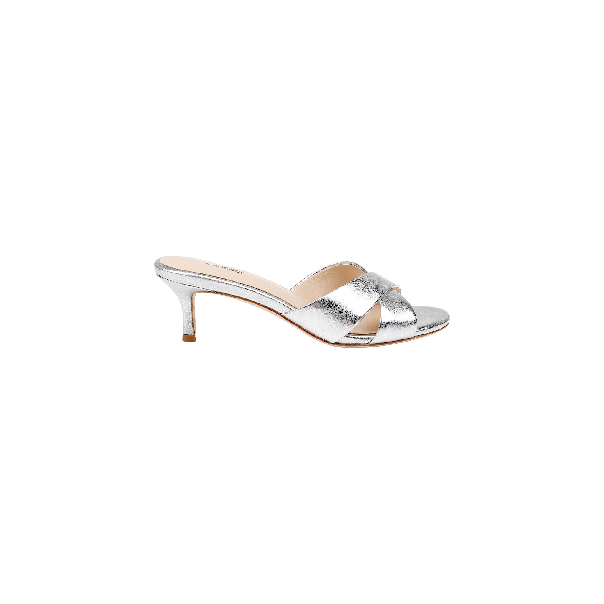 The Aveline Kitten-Heel Sandal is a silver mule crafted from metallic leather, featuring crisscross straps and a strappy vamp with an open toe, shown in a side view against a white background.