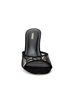The Avery Lace Open-Toe Mule, shown from the front against a white background, features black lace detailing and an open-toe design with a suede sole.