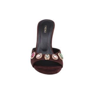 The Avery Suede Open-Toe Mule is a mahogany brown sandal featuring a dark brown suede upper, a black insole, and vibrant multicolored jeweled embellishments on the front strap. Captured from above on a white background, this open-toe silhouette radiates elegance and charm.