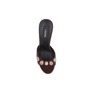 The Avery Suede Open-Toe Mule in luxurious mahogany brown suede is displayed from a top-down perspective against a white background, showcasing its L’AGENCE-branded insole and a strap adorned with multicolored jewel embellishments.