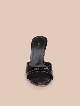 The Avery Leather Open-Toe Mule is a single chic sandal in black with a crocodile pattern and an open toe, shown from the front on a beige background; this sculpted stiletto mule exudes modern elegance.