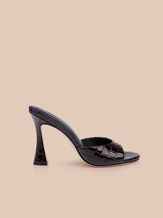 The Avery Leather Open-Toe Mule, crafted from luxurious burgundy crocodile-embossed leather, features a wide front strap, sculpted stiletto heel, and open-toe design. Displayed on a neutral beige background, this sophisticated mule showcases a modern silhouette and effortlessly chic style.