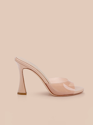 The Avery Open-Toe Mule is a light nude, high-heeled mule sandal with a clear vamp, glossy finish, open toe, and sculpted stiletto silhouette, shown against a matching beige background.