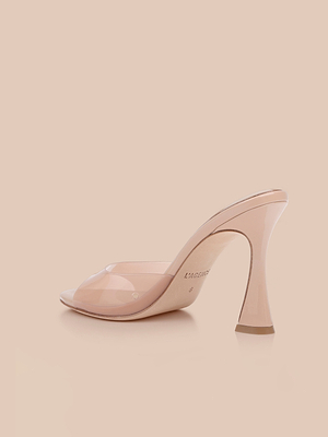 The Avery Open-Toe Mule is a sculpted stiletto with light nude heels, a clear vamp, and a glossy finish, shown against a plain beige background.