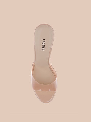 The Avery Open-Toe Mule is a nude heeled sandal with a clear vamp strap and sculpted stiletto, shown from above on a beige background. The insole is labeled LAGENCE.