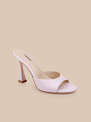The Avery Leather Open-Toe Mule, in light pink with a slip-on design and sculpted heel, is showcased against a plain beige background.