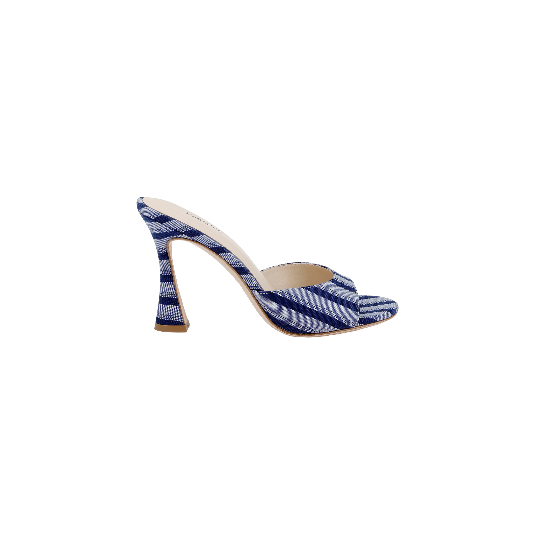 The Avery Open-Toe Mule showcases a blue striped denim upper with an open-toe silhouette and a distinctive curved stiletto heel, displayed against a plain white background.