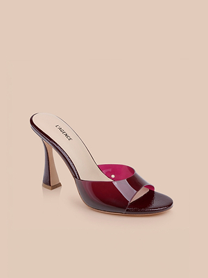 The Avery Open-Toe Mule features a glossy burgundy strap and beige insole with LAGENCE branding. This sculpted stiletto sandal is showcased against a neutral beige background for an elegant look.