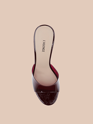 The Avery Open-Toe Mule is a chic maroon sandal featuring a clear strap and LAGENCE branding on the beige insole, shown from above on a plain beige background.