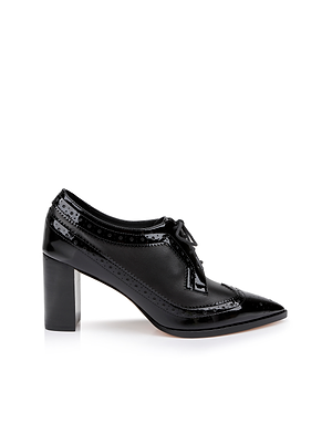 The Elodie Leather Oxford Pump, a black leather shoe with a pointed toe, decorative perforations, lace-up front, and chunky block heel, is shown on a white background.