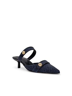 The Gilliane Heeled Mule by L'AGENCE is a navy blue pointed-toe denim mule with a slingback heel, black trim, and two gold lion-embossed buttons on the straps. It features a low, thin heel and an elegant, modern design with vintage appeal.