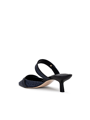The Gilliane Heeled Mule by L'AGENCE is a vintage-inspired dark denim mule featuring a pointed toe and slim black kitten heel, shown from the rear against a white background.