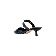 The Gilliane Heeled Mule is a vintage-inspired shoe crafted from dark denim, featuring a pointed toe, open back, and a mid-height black kitten heel. It is shown from the rear at an angle on a plain white background.