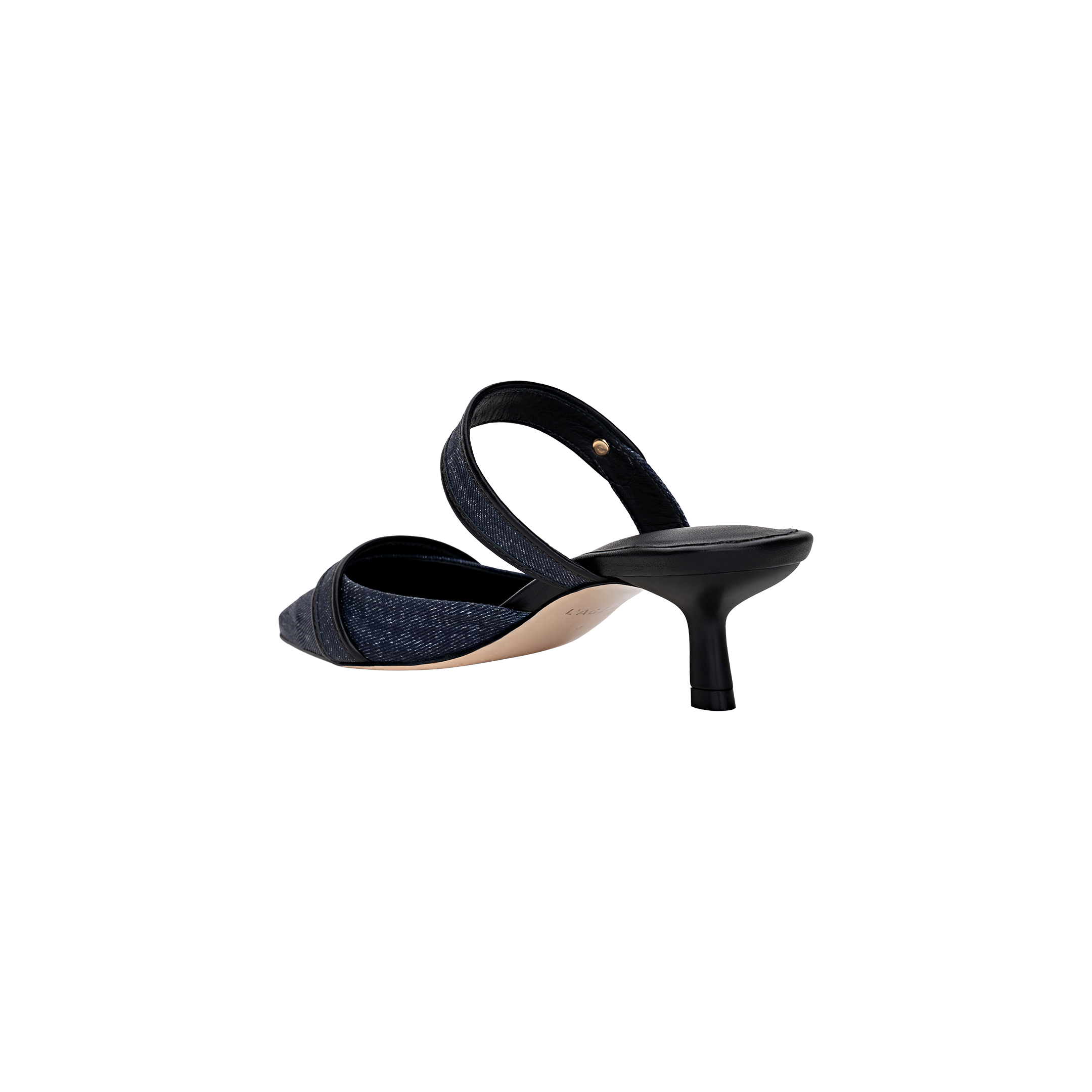 The Gilliane Heeled Mule is a vintage-inspired shoe crafted from dark denim, featuring a pointed toe, open back, and a mid-height black kitten heel. It is shown from the rear at an angle on a plain white background.