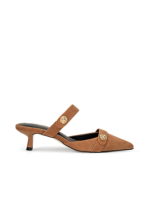 The Gilliane Heeled Mule is a tan suede mule featuring a pointed toe, low kitten heel, and two lion-embossed buttons on the front and strap, shown on a white background.