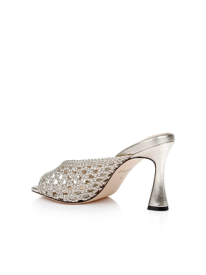 The Jacques Leather Mule is a silver high-heeled mule with an open toe, a woven leather upper, and a sculptural flared heel, shown against a white background.