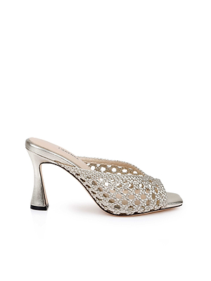 The Jacques Leather Mule is a silver open-toe mule with a sculptural flared heel and woven cut-out upper, shown in side view against a white background.