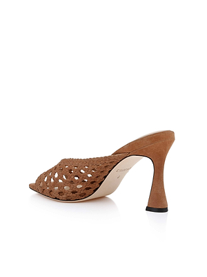 The Jacques Suede Mule features brown woven suede, an open toe, V-cut vamp, and a sculptural flared high heel, displayed on a white background at a slight rear angle.