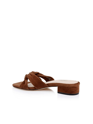 The Lea Suede Knot Sandal is a brown slip-on mule with a low block heel, twisted knot front strap, and plush memory foam cushioning, shown against a white background.