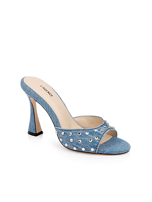 The Lucienne Embellished Denim Mule showcases blue denim, silver studded strap, open toe, and a chic square heel for standout style.