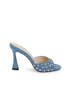 The Lucienne Embellished Denim Mule features an open toe, silver rivet details, a flared heel, and plush memory foam cushioning, all showcased on a plain white background.