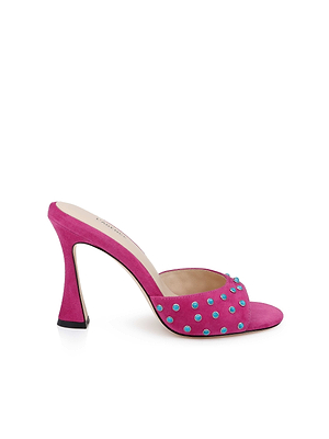 The Lucienne Embellished Suede Mule is a bright pink magenta suede mule with a curved open-toe heel and turquoise embellishments on the front strap, shown on a white background.