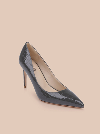 The Maelle Leather Pump, crafted in black crocodile-embossed leather with a pointed toe and stiletto heel, is displayed against a light peach background.