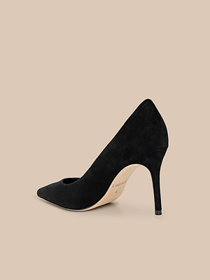 The Maelle Suede Pump, a classic black pointed-toe stiletto, is displayed against a beige background from a back side angle.
