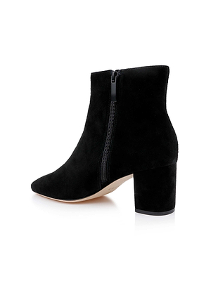 The Melanie Suede Bootie is a black ankle bootie with a side zipper and chunky block heel, displayed against a white background.