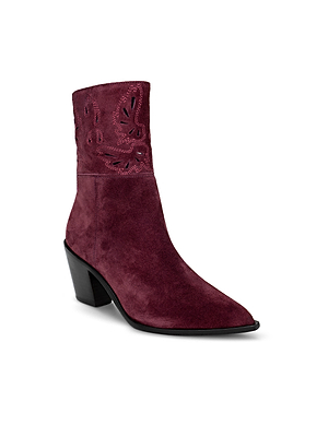 The Anne Western Bootie features a pointed toe, maroon suede, a mid-height block heel, and decorative cut-out patterns near the shaft for a modern Western-inspired look.