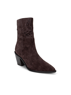 The Anne Western Bootie is a dark brown suede bootie inspired by Western boots, featuring a pointed toe, block heel, and subtle decorative stitching near the top.