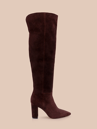 The Nanette Boot, a single knee-high boot in soft mahogany brown suede with a pointed toe and chunky high heel, is displayed against a plain beige background.