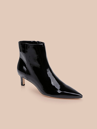 The Lilly Kitten-Heel Bootie, crafted in black patent leather with a pointed toe and a short kitten heel, is displayed on a plain beige background.