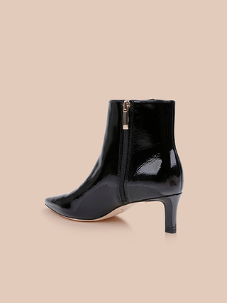 The Lilly Kitten-Heel Bootie features glossy black patent leather with a pointed toe, side zipper, and mid-height heel, showcased against a light beige background.