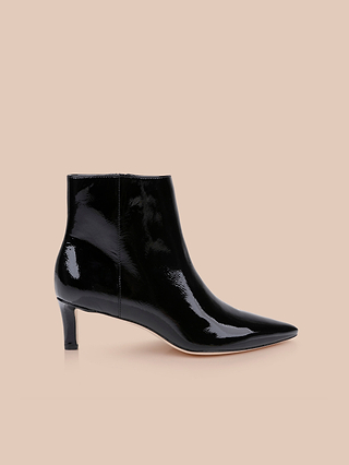 The Lilly Kitten-Heel Bootie, crafted in shiny black patent leather with a pointed toe and a short, slender kitten heel, is displayed on a neutral beige background.