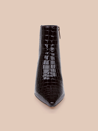 The Lilly Kitten-Heel Bootie is shown from the front, featuring black, shiny, crocodile-embossed leather with a pointed toe and set against a beige background.