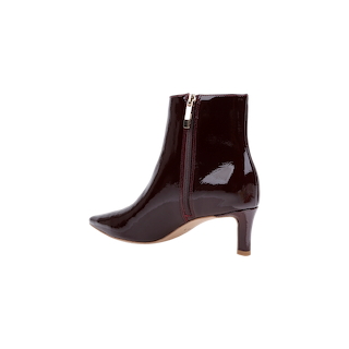 The Lilly Kitten-Heel Bootie, crafted in shiny dark burgundy patent leather with a pointed toe, mid-height heel, and convenient side zipper, is an elegant city boot displayed on a white background.
