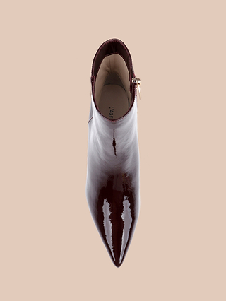 La bottine à talon bas « Lilly », confectionnée en cuir verni bordeaux brillant et dotée dun bout pointu, est présentée vue de dessus sur un fond beige.